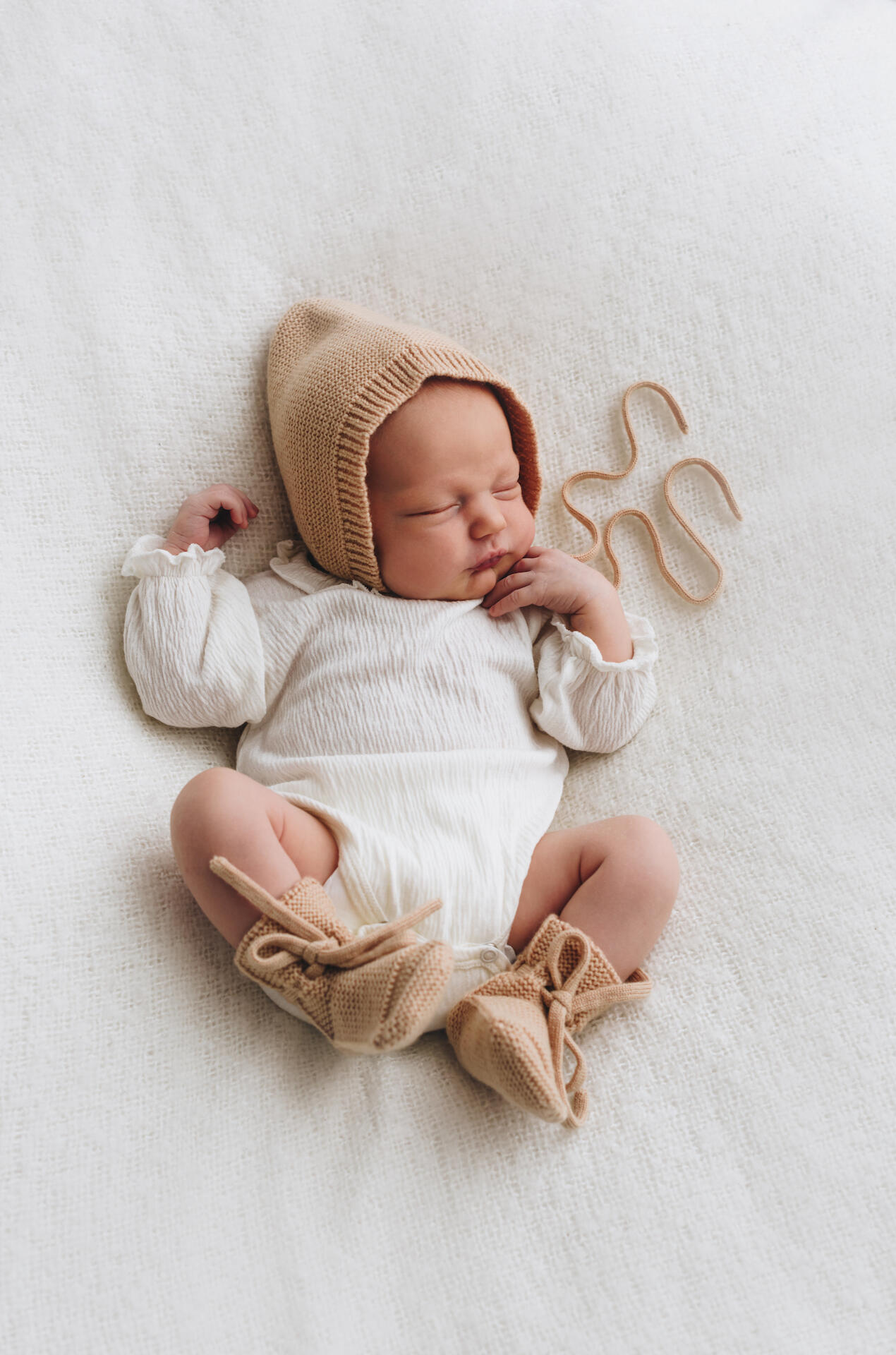 Sesja noworodkowa w studio w Krakowie – śpiące niemowlę w jasnej owijce, fotografia Anny Janowskiej